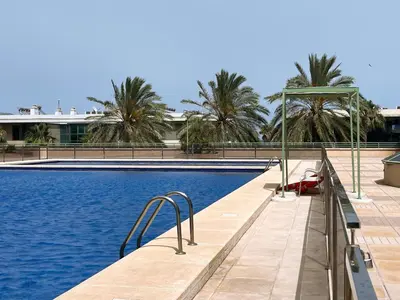 a swimming pool with palm trees in the background at Stylish well-connected beachfront flat in Valencia