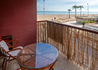 a table and chairs on a balcony overlooking the beach at Apartamento Arenal 1a Linea de Playa in Cullera