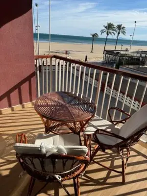 two chairs and a table on a balcony with a beach at Apartamento Arenal 1a Linea de Playa in Cullera