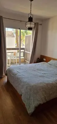 a bedroom with a bed and a view of a patio at Apartamento en complejo residencial con piscina in Puebla de Farnals