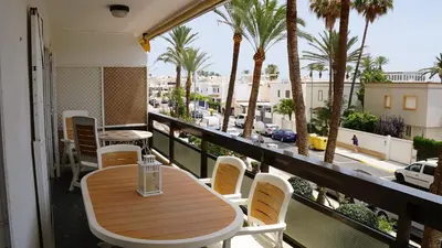 a balcony with a table and chairs and palm trees at Apartamento en complejo residencial con piscina in Puebla de Farnals