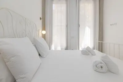 a white bed with white pillows and towels on it at ApartUP Ca La Leni Beach I in Valencia