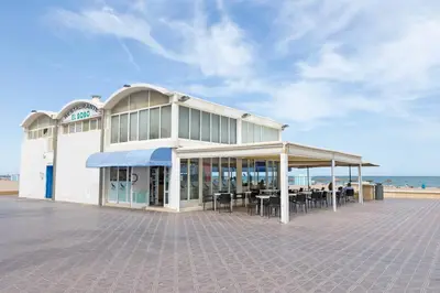 a building with tables and chairs in front of the beach at ApartUP Ca La Leni Beach I in Valencia