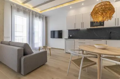 a kitchen and living room with a table and a couch at ApartUP Ca La Leni Beach III in Valencia