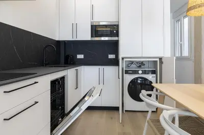a kitchen with white cabinets and a washer and dryer at ApartUP Ca La Leni Beach II in Valencia