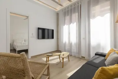 a living room with a couch and a tv on a wall at ApartUP Ca La Leni Beach II in Valencia