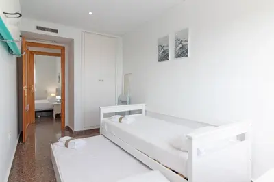 a white room with two beds and a bathroom at Global Vacacional, Bonito apartamento en Puerto de Sagunto cerca de la playa in Puerto de Sagunto