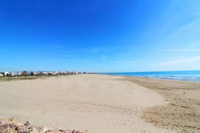 a sandy beach with a city in the background at Global Vacacional, Bonito apartamento en Puerto de Sagunto cerca de la playa in Puerto de Sagunto
