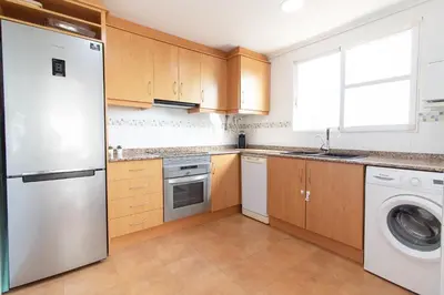 a kitchen with a refrigerator and a dishwasher at Global Vacacional, Bonito apartamento en Puerto de Sagunto cerca de la playa in Puerto de Sagunto