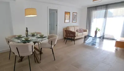 a dining room and living room with a table and chairs at Piso nuevo y luminoso ESTANCIAS DE TEMPORADA Mín 12 noches in Valencia