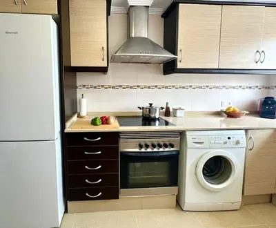 a kitchen with a stove and a washing machine at Vacaciones con el Mediterráneo a menos de 50 metros in Cullera