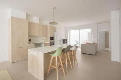 a kitchen with wooden cabinets and a counter with stools at Casa Ramona Ruzafa Valencia Centro in Valencia