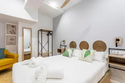 a bedroom with a large white bed and a yellow chair at Marie Curie Flats, Lovely Duplex 3 in Valencia