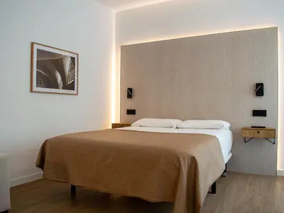 a bedroom with a large bed with a brown blanket at Guastavino by Alma Suites in Valencia