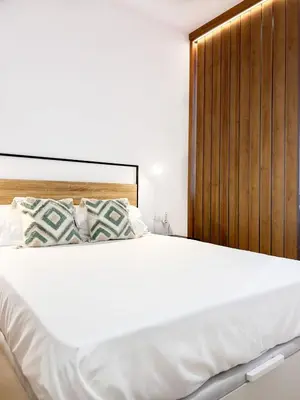 a bedroom with a white bed with a wooden headboard at Apartamento junto a Ruzafa cerca del centro in Valencia