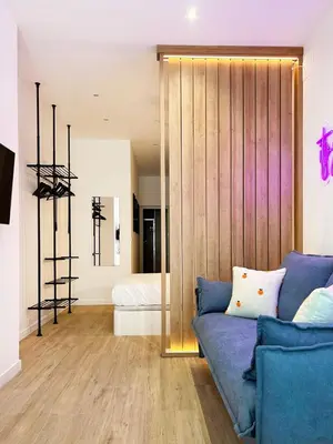 a living room with a blue couch and a bedroom at Apartamento junto a Ruzafa cerca del centro in Valencia
