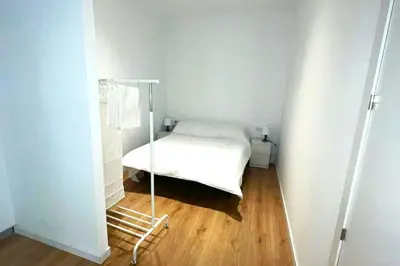 a small white bedroom with a bed and a wooden floor at Apartamento Cienciasmar in Valencia