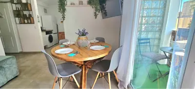 a dining room table with chairs and a vase with flowers at Urban loft Valencia playa in Puebla de Farnals