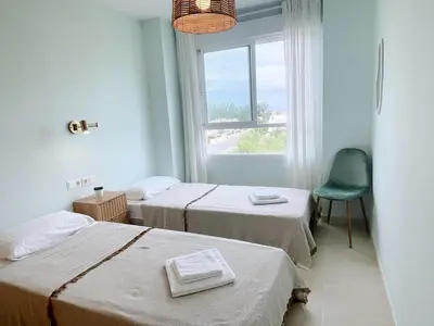 a room with two beds and a chair and a window at Marinao Apartment in Playa Pobla de Farnals