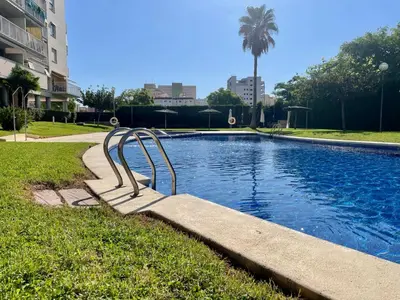 a swimming pool with a metal rail next to a building at Marinao Apartment in Playa Pobla de Farnals