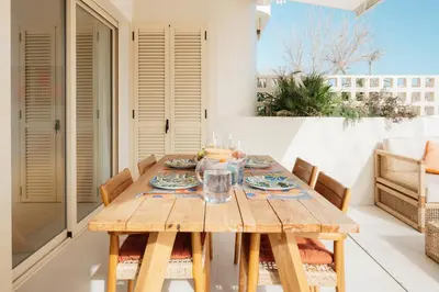 a wooden table with plates and glasses on it on a patio at Terrasses - Beach apartment with swimming pool in Puzol