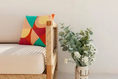 a vase of flowers next to a chair with a pillow at Terrasses - Beach apartment with swimming pool in Puzol