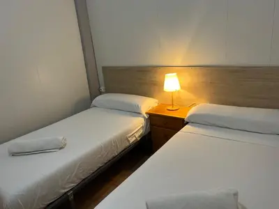 two beds in a room with a lamp on a table at BajoPlaya in Burriana