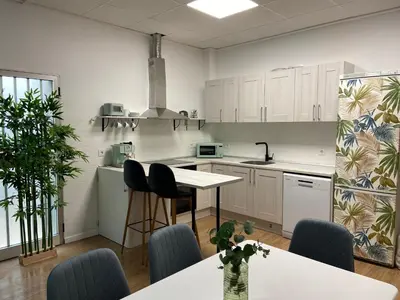 a kitchen with white cabinets and a table and chairs at BajoPlaya in Burriana