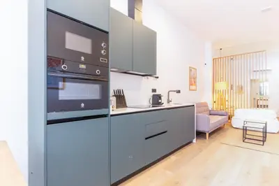 a kitchen with a stove top oven next to a living room at Mestalla Flats by Nomad Host in Valencia