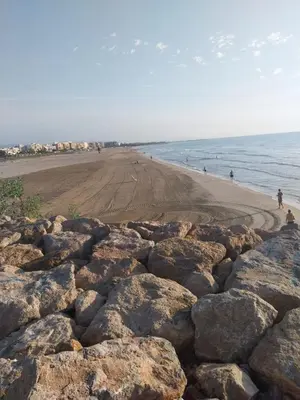 a beach with rocks and people walking on the beach at Casa Bonita de Gisela in Puerto de Sagunto
