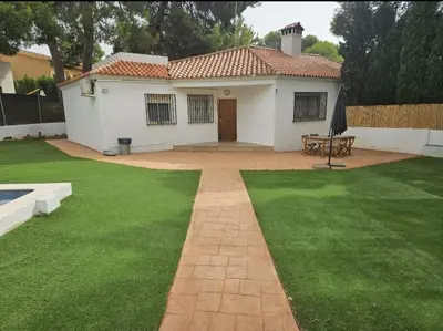 a small white house with a green lawn at La Cañada in Partida de La Cañada