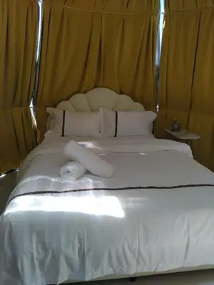 a bed with white sheets and pillows on it at J&L Glamping in La Presa