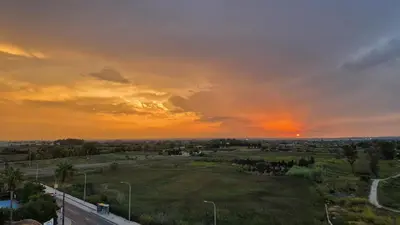 a sunset over a field with a road at Panorama Azul Apartment in El Puig