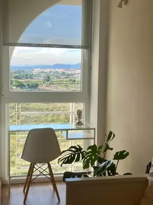 a room with a window with a plant and a chair at Panorama Azul Apartment in El Puig