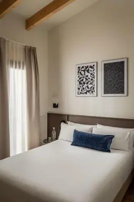 a bedroom with a large white bed with a blue pillow at BYPILLOW Sinfonía in Valencia