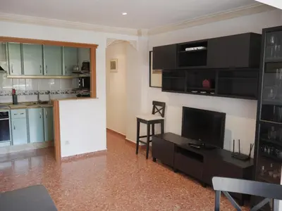 a living room with a tv and a kitchen at Malvarrosa, 1-6 in Cullera