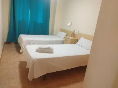 two beds in a room with blue curtains at Apartamento cerca del puerto deportivo 1 in Burriana