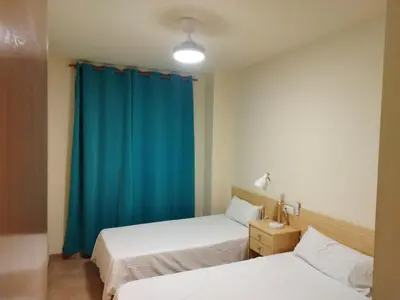 a bedroom with two beds and a blue curtain at Apartamento cerca del puerto deportivo 1 in Burriana