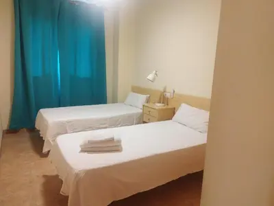 two beds in a room with blue curtains at Apartamento cerca del puerto deportivo 1 in Burriana