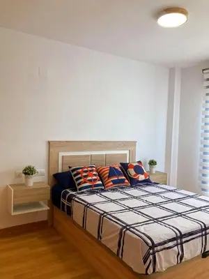 a bedroom with a bed with colorful pillows on it at Cozy apartment near the beach in Puerto de Sagunto