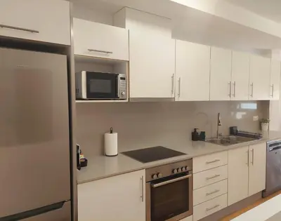 a kitchen with white cabinets and a microwave at Cozy apartment near the beach in Puerto de Sagunto