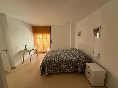 a bedroom with a bed and a table and a window at VIVIENDA La MERCED in El Puig