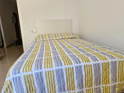 a bed with a yellow and blue comforter in a room at VIVIENDA La MERCED in El Puig
