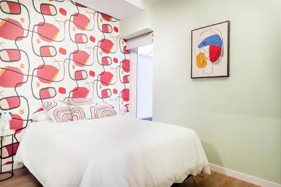 a bedroom with a white bed and a red and white wall at Apartamento B Cube by Mimood Aparthotels in Valencia
