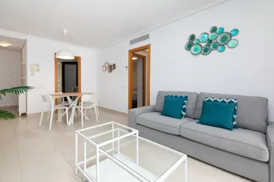 a living room with a couch and a table at ApartUP Patacona Palm Beach II in Valencia
