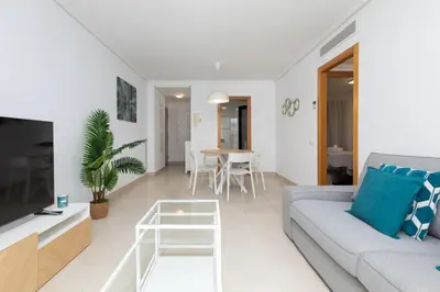 a living room with a couch and a table at ApartUP Patacona Palm Beach II in Valencia