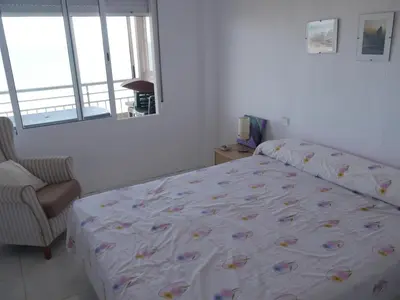 a bedroom with a bed and a chair and a window at HAWAI, Esc-3, 3-16 in Faro de Cullera