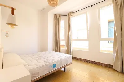a bedroom with a bed and two windows at Tradición y modernidad Casa de pueblo junto al mar in Puerto de Sagunto