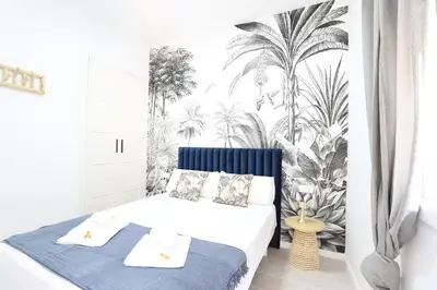a bedroom with a bed with a mural of palm trees at Deslumbrante y familiar casa cerca de la playa in Puerto de Sagunto