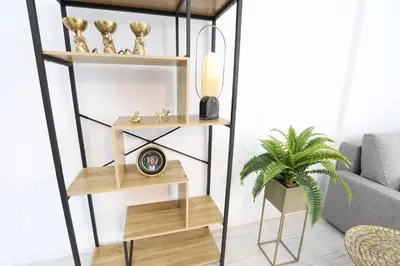 a shelf with a clock and a plant in a room at Deslumbrante y familiar casa cerca de la playa in Puerto de Sagunto